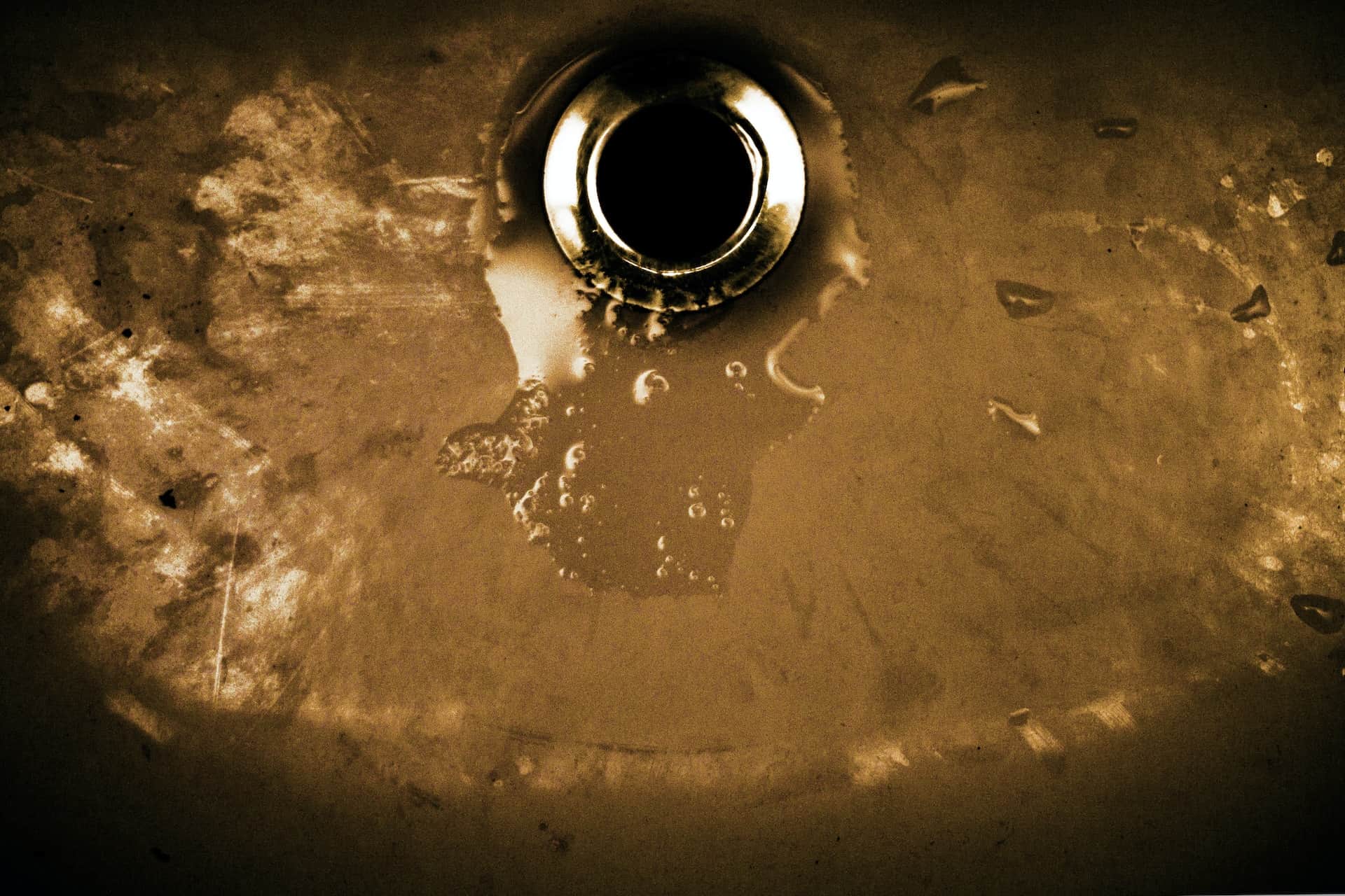 A plughole or drain surrounding by water.